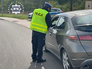 Zdjęcie przedstawia policjanta ruchu drogowego podczas kontroli drogowej